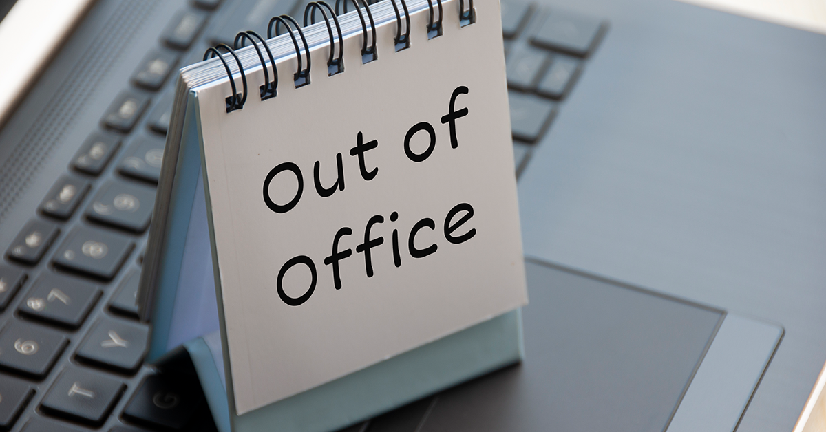 Out of office text on calendar desk on top of a laptop