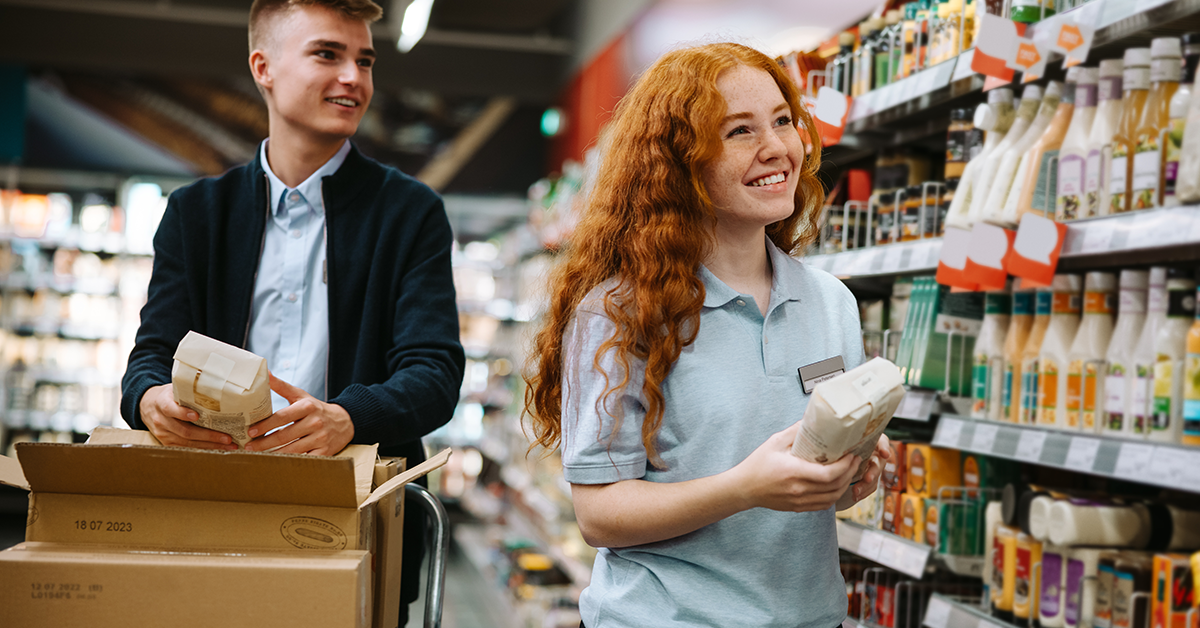 Two young workers stocking a grocery shelf