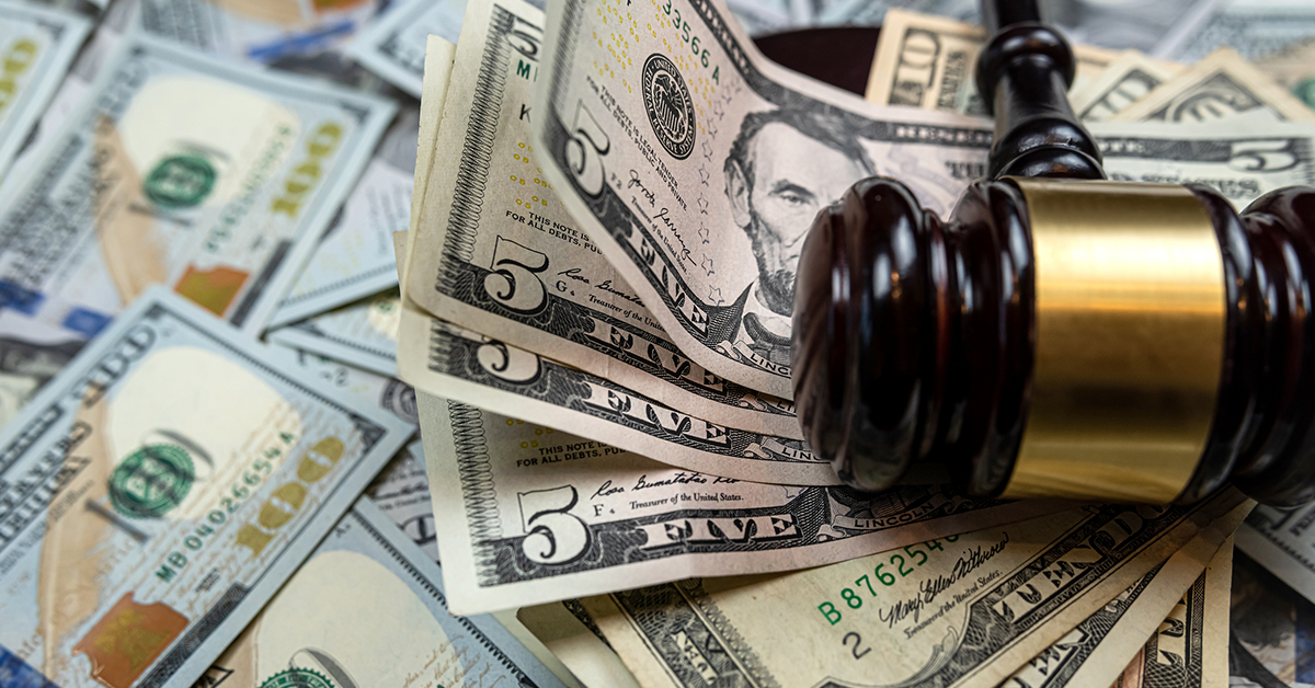 Stack of five dollar bills, gavel lying on top of money