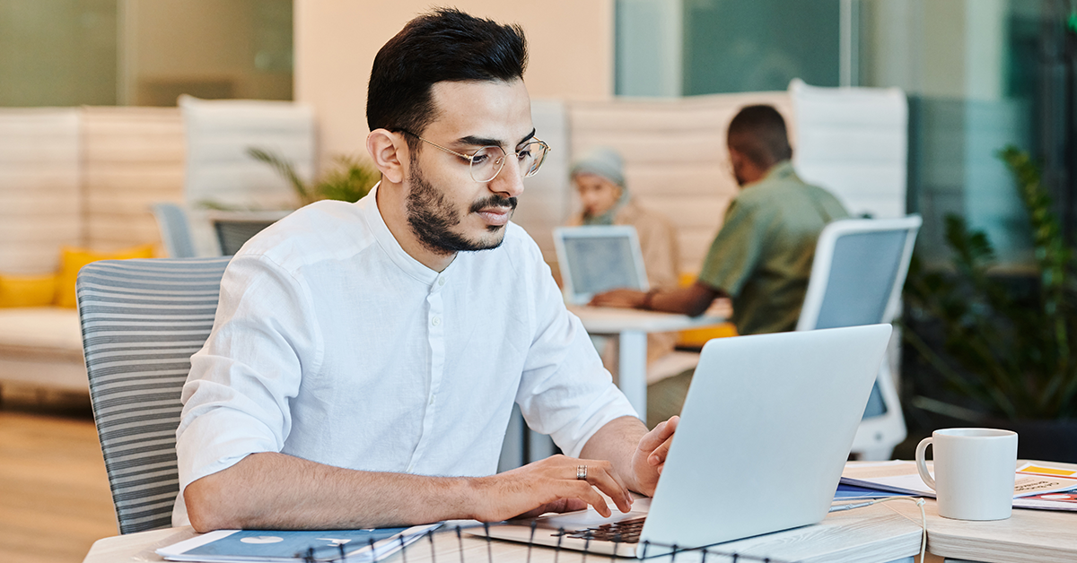 Man working in an office, coworkers in background