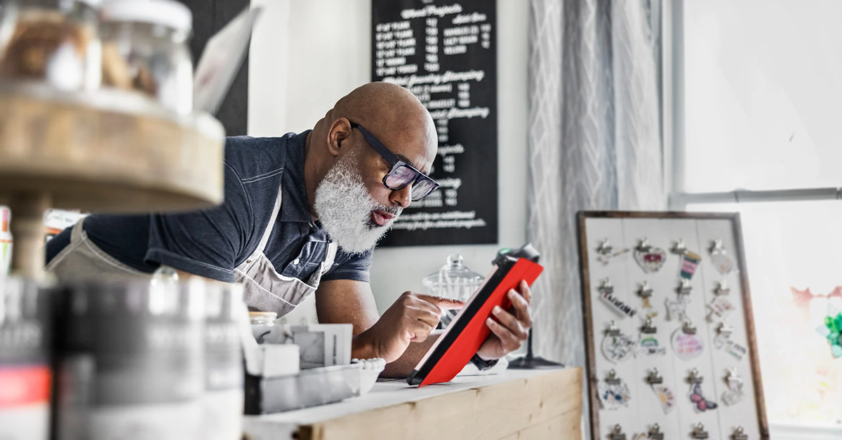 Man behind a counter, working on tablet