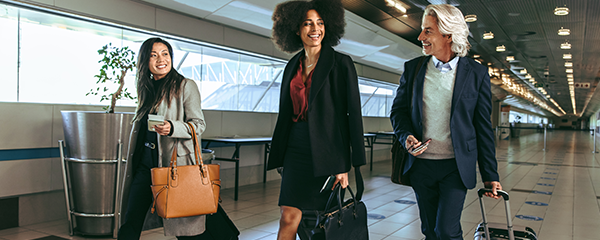 Group of business people going on business trip carrying suitcases while walking through airport passageway