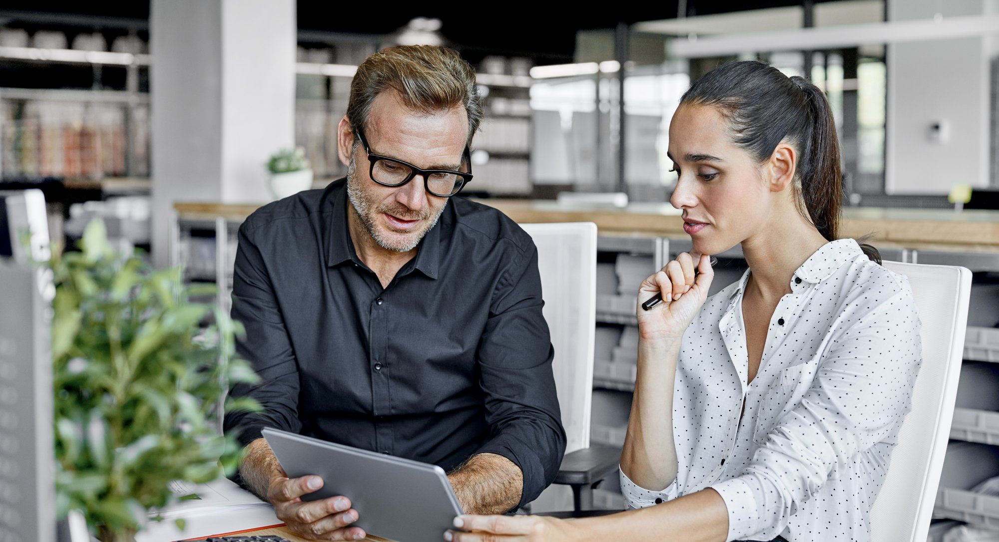 Two coworkers look at a tablet together