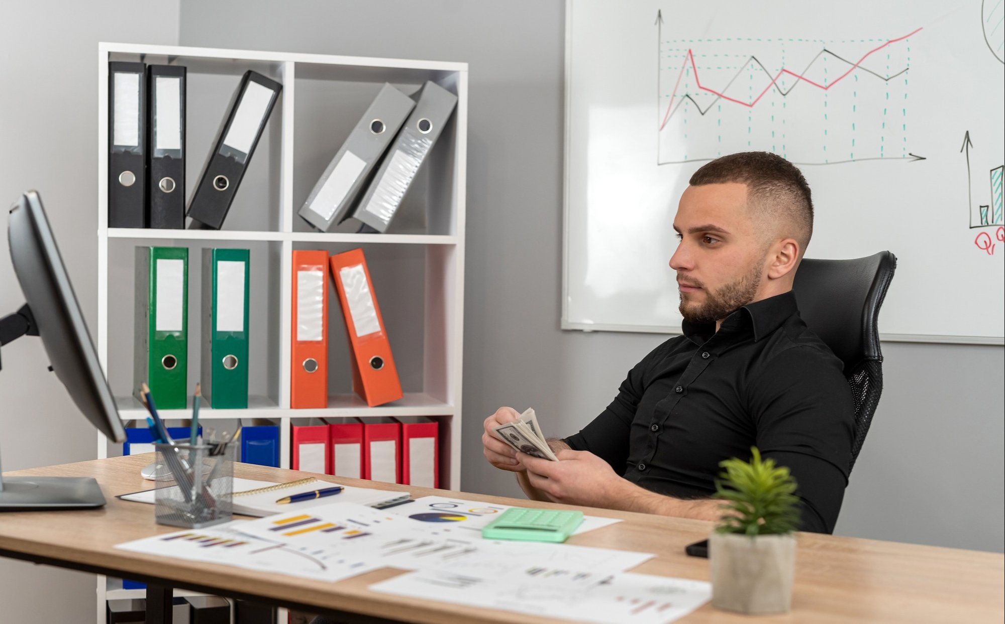 A worker sits at their desk, counting money
