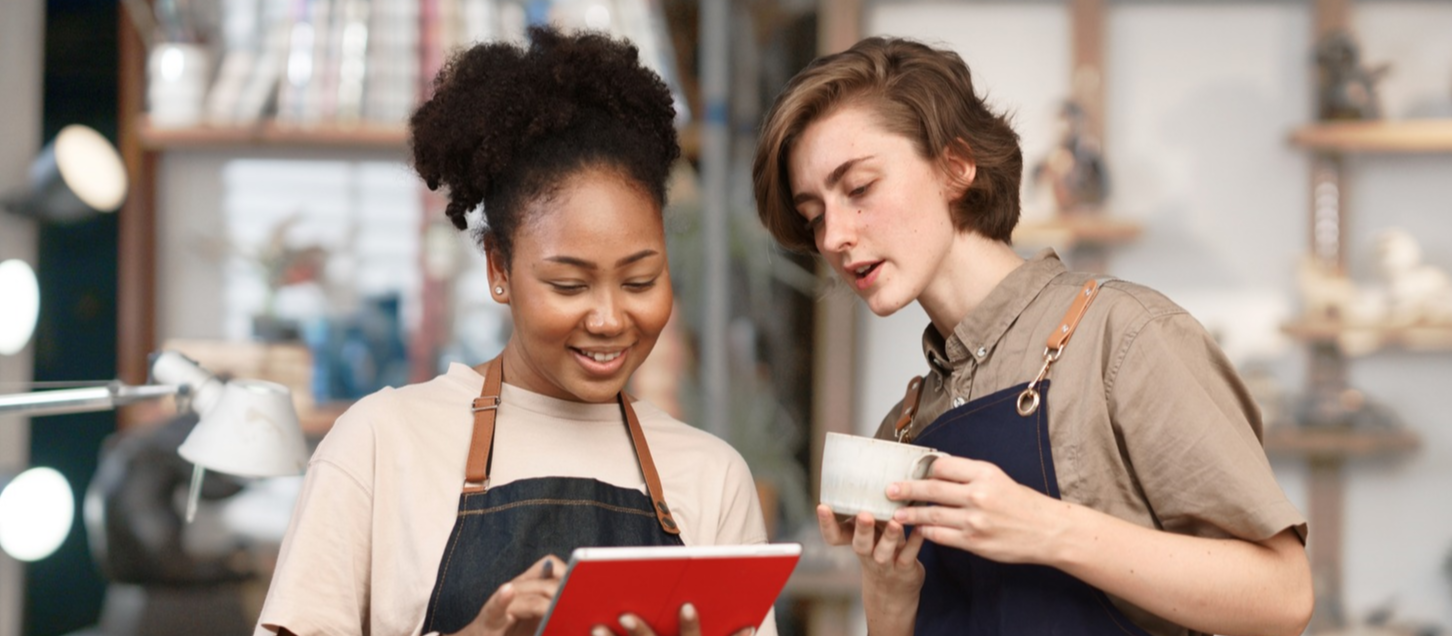 Coworkers reviewing tablet in a cafe Coworkers reviewing tablet in a cafe
