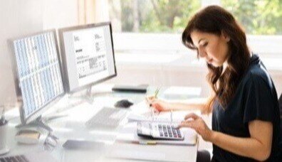 Woman at desk, using a calculator 