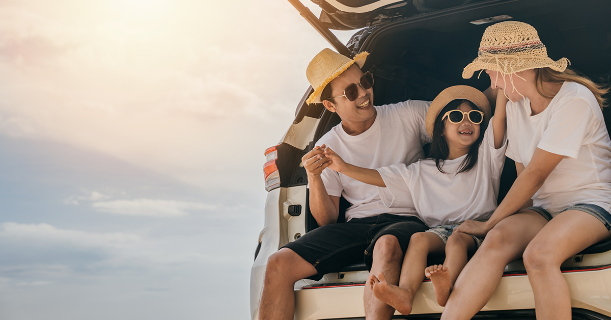 Family sitting in the back of a car, happy during the summer 