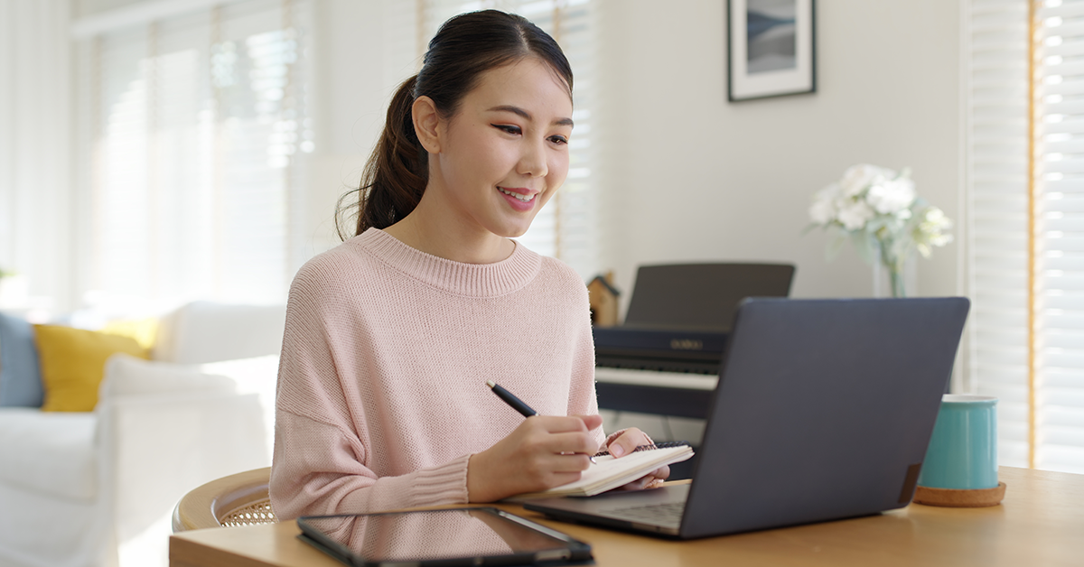 Woman working remotely from home sitting smiling in cozy workspace