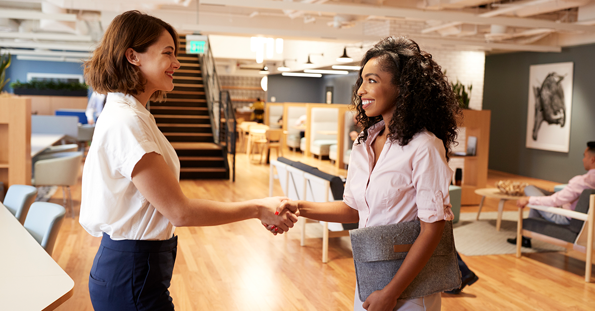 Two Businesswomen Meeting and Shaking Hands in Modern Office