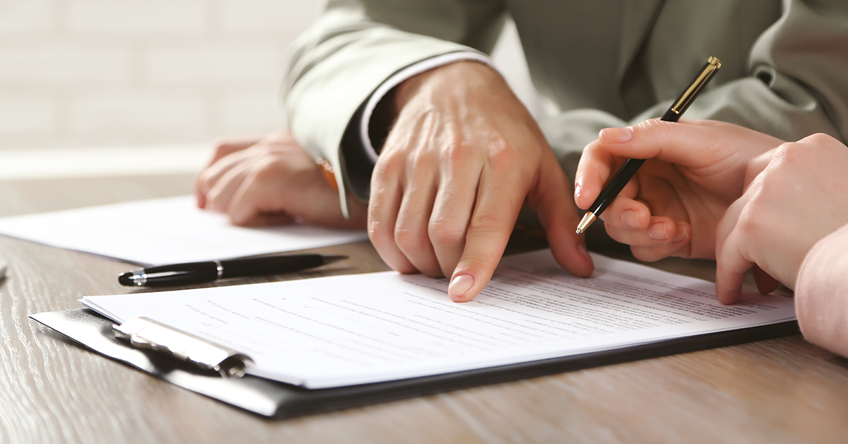 Closeup of hands working, signing documents at a desk