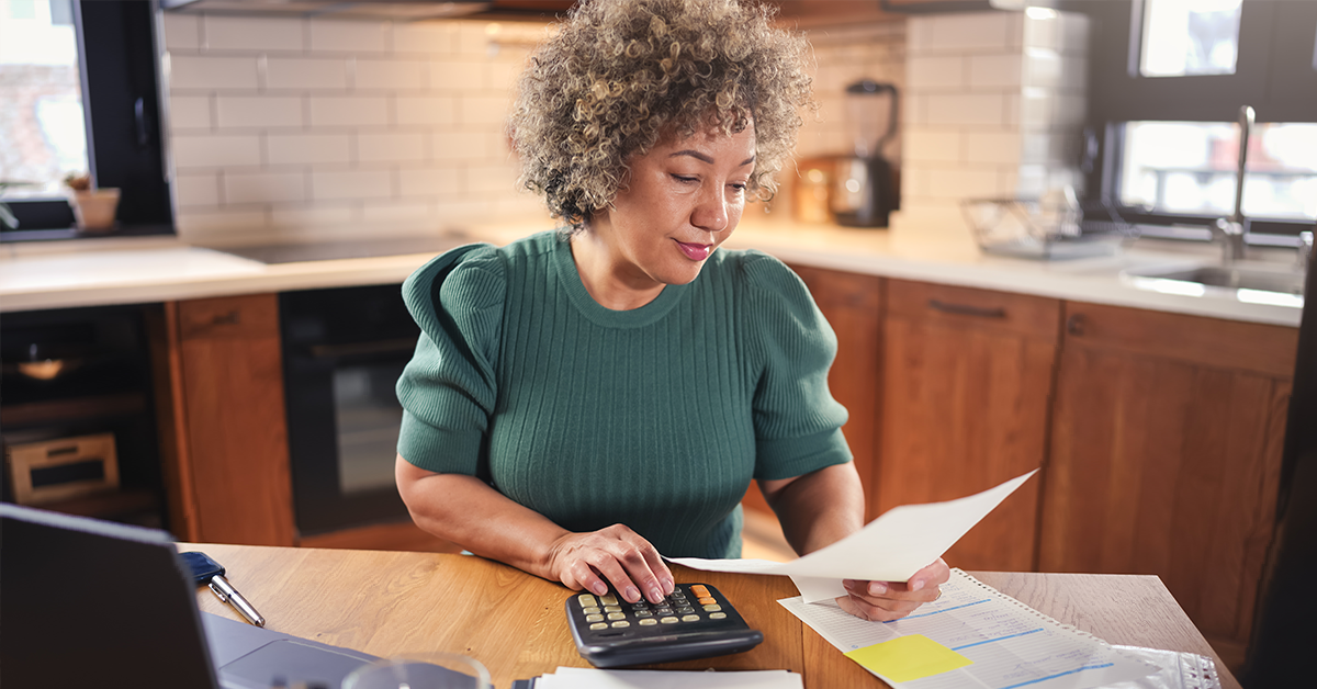 Woman working at desk, calculating expenses