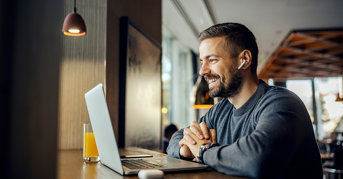 Remote worker sitting in a coffee shop, having conference call.