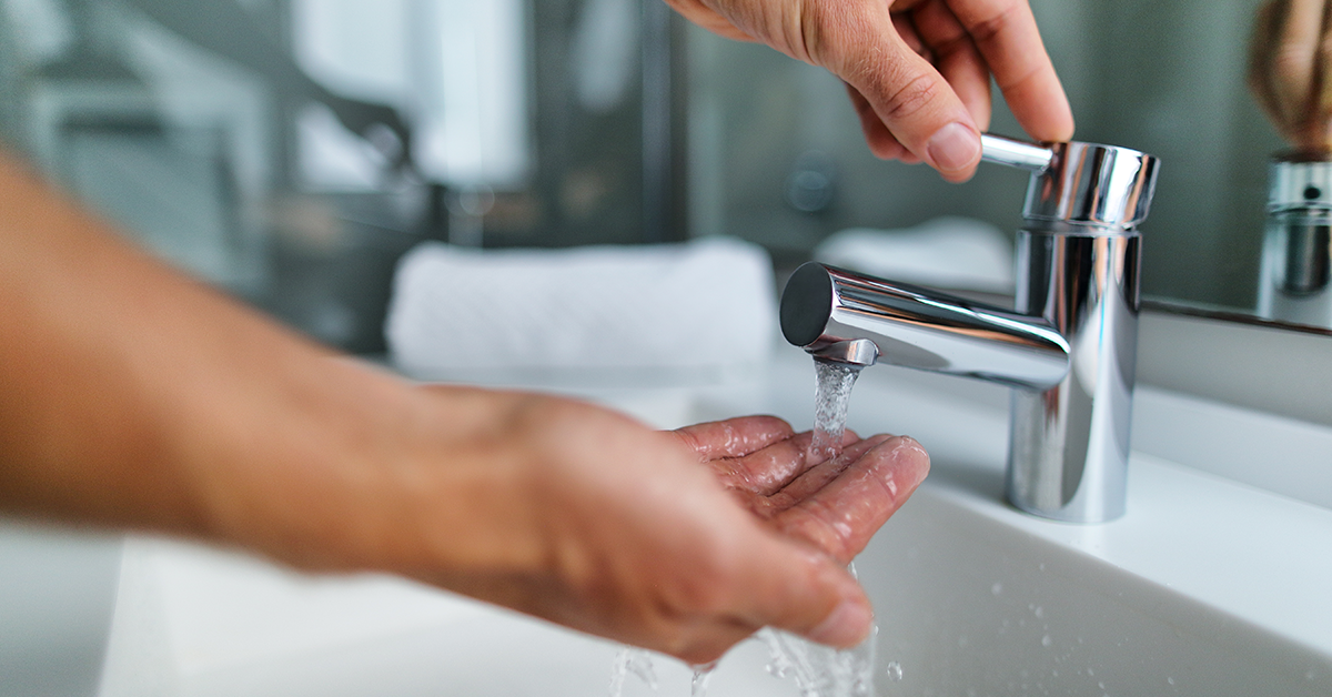 Man washing hands in bathroom sink