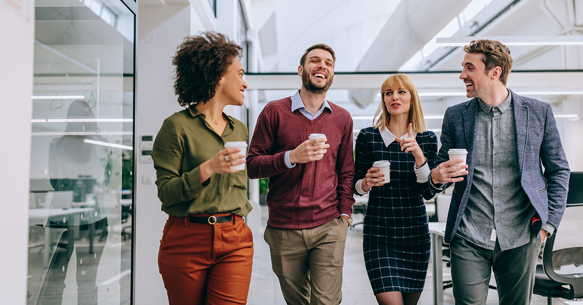 Group of coworkers laughing in conversation, drinking coffee