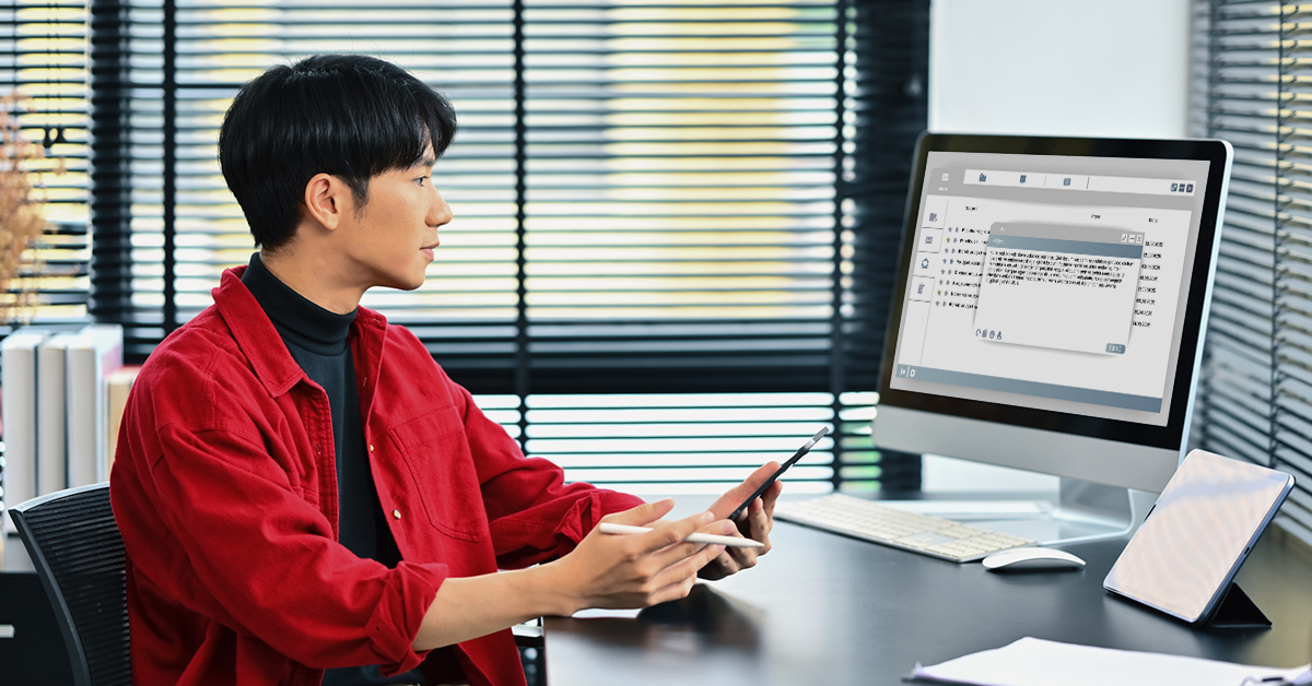 Man at desk, checking emails and working on cell phone