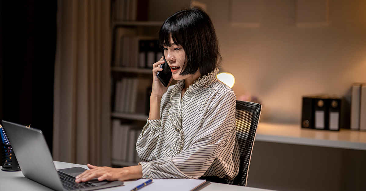 Young businesswoman talking on the phone and working late at night in her home office