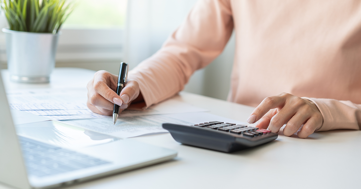 Hands of young woman using calculator to budget expenses