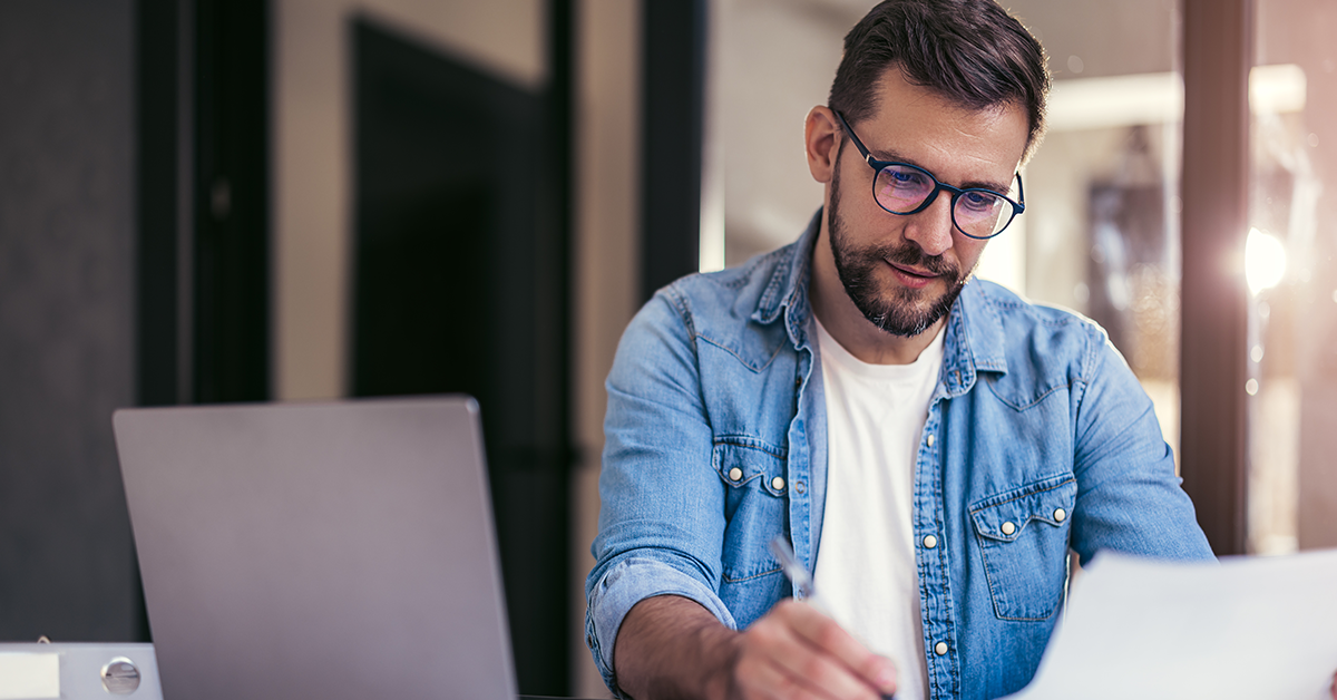 Man with glasses working at desk and doing paperwork 