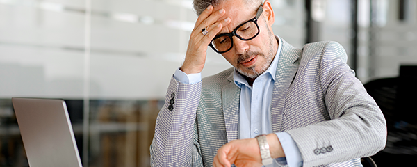Businessman looking at the watch on his wrist and worrying about the time
