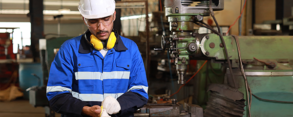 Technician in protective uniform, putting on gloves at manufacturing factory
