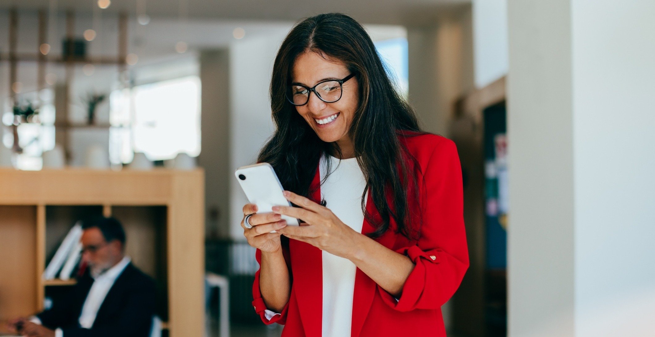 A woman in red, smiling at her phone.