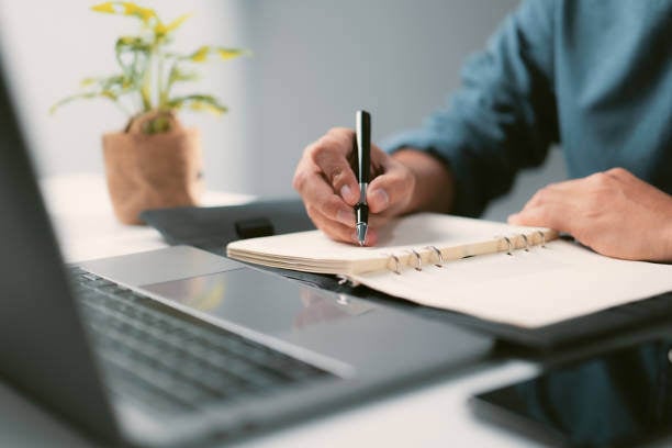 A person writing by hand in a notebook.