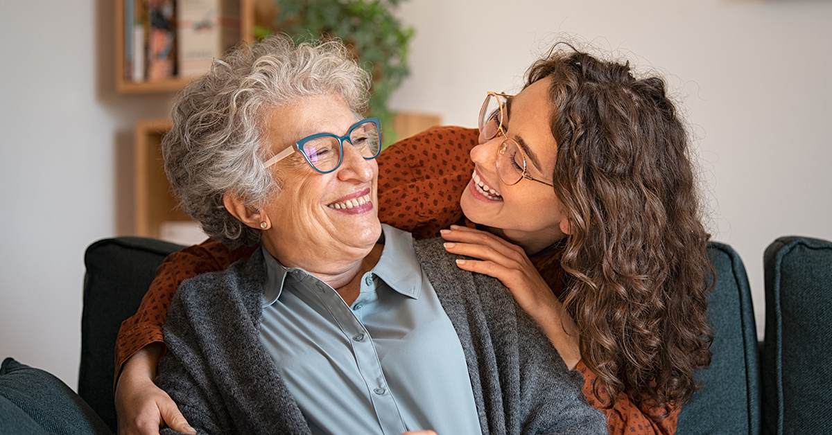 Grandmother and granddaughter laughing and embracing at home